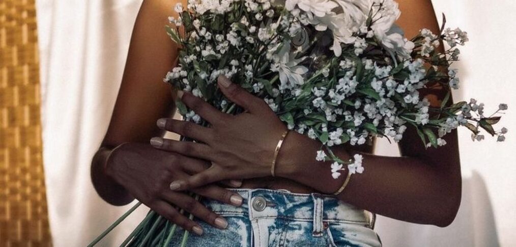 A BLACK LADY HOLDING FLOWERS TO COVER HER BREAST