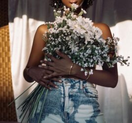 A BLACK LADY HOLDING FLOWERS TO COVER HER BREAST