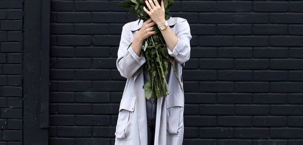 A GIRL HOLDING FLOWERS COVERING HER FACE