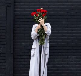 A GIRL HOLDING FLOWERS COVERING HER FACE