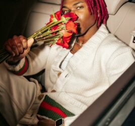 joe boy smelling roses in a car wearing white